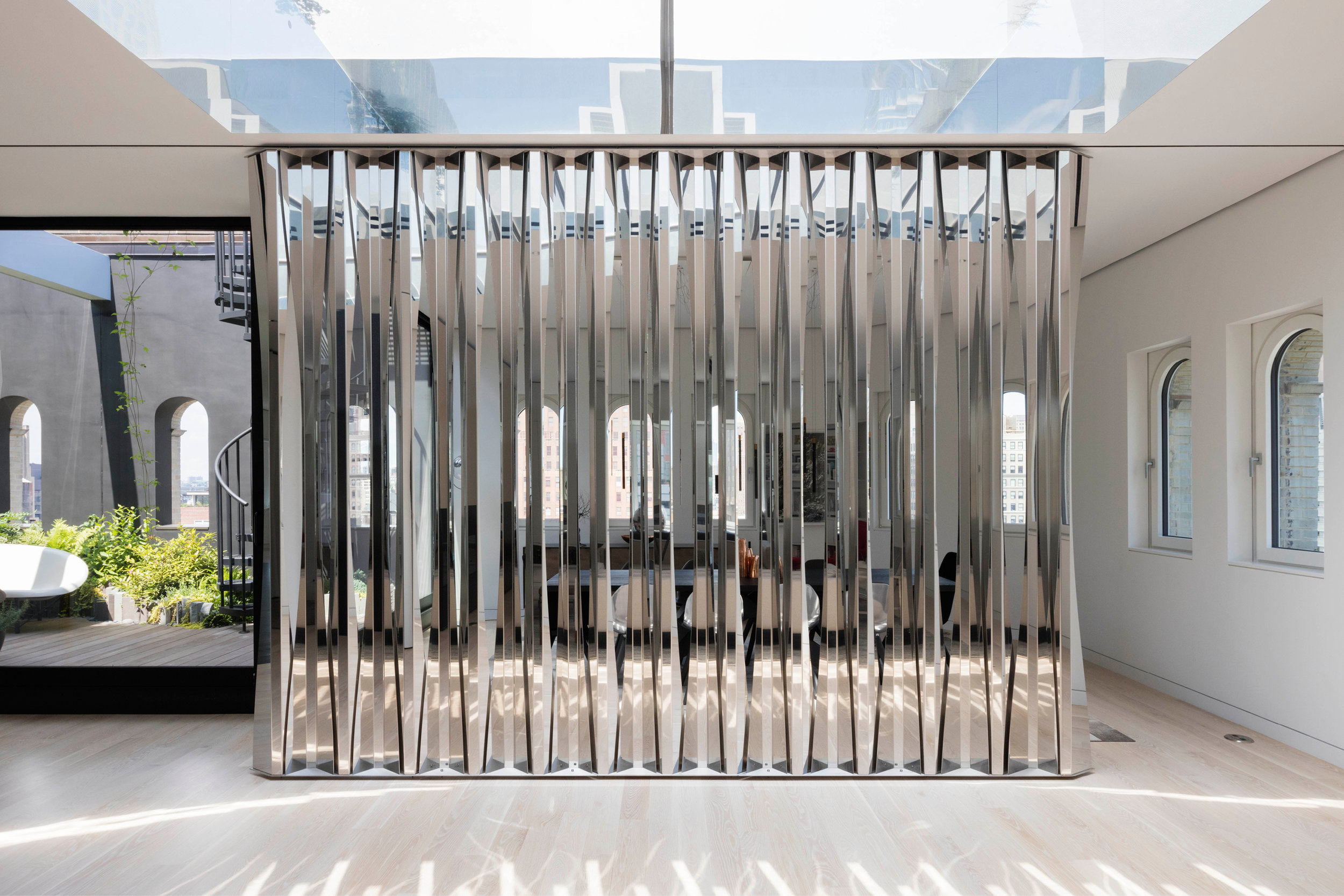 Faced stainless steel folding screen offers privacy to the dining room at the Gerken Loft, designed by Young Projects
