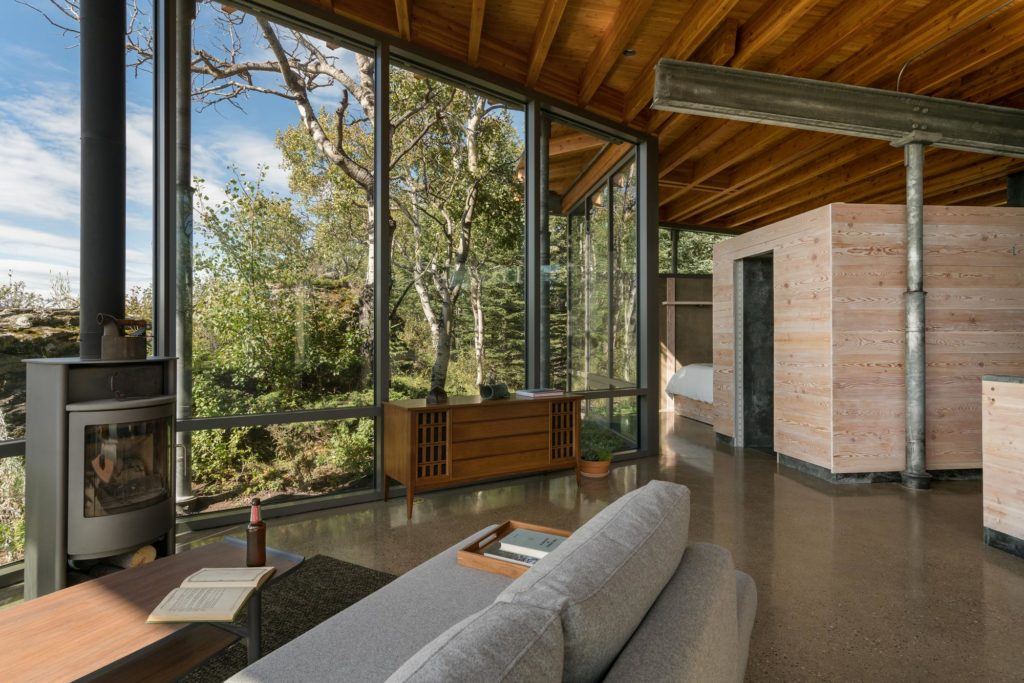 Full-height windows bathe Rock House's living room in warm sunlight